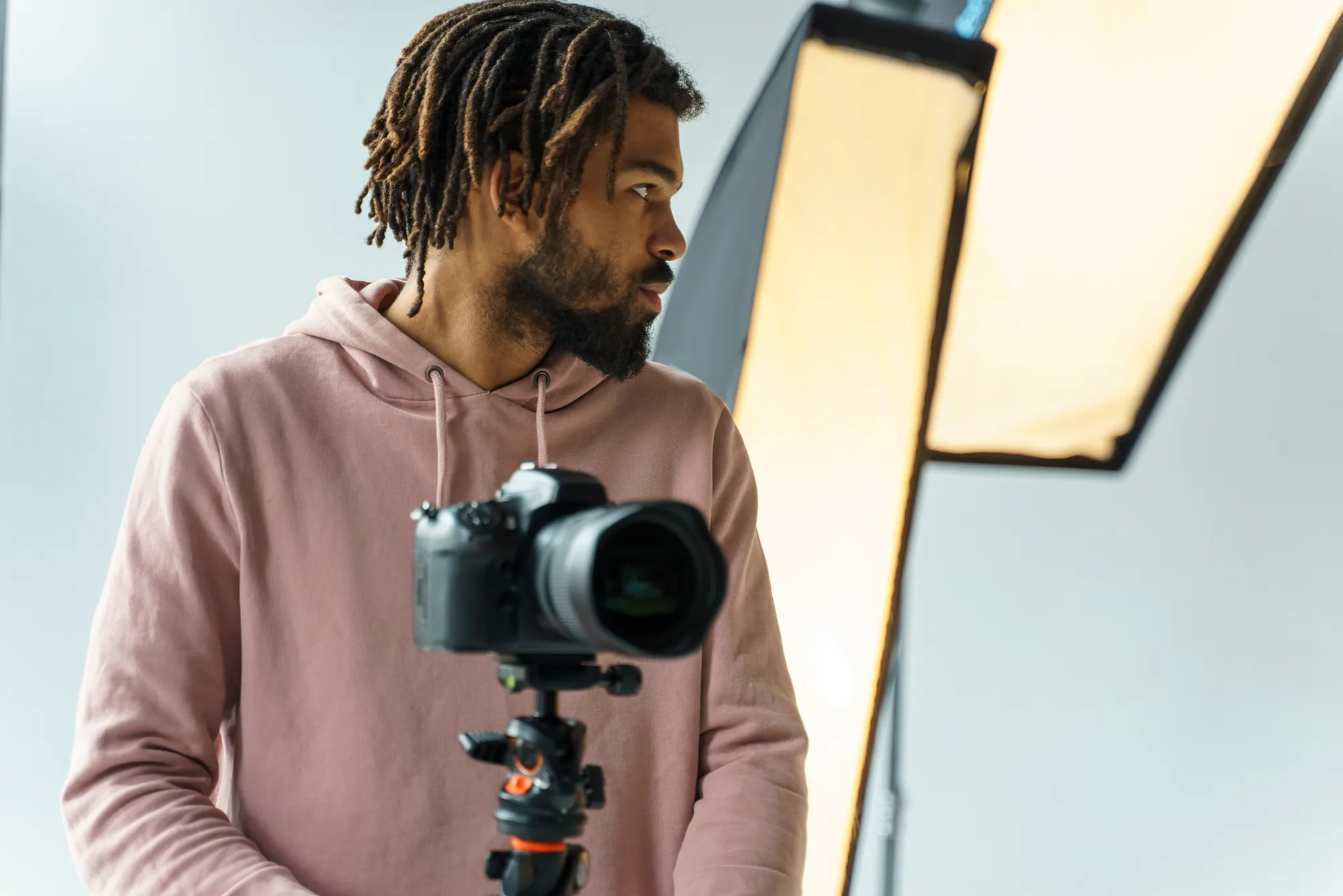 A film-maker beside a camera on a tripod in a lit studio