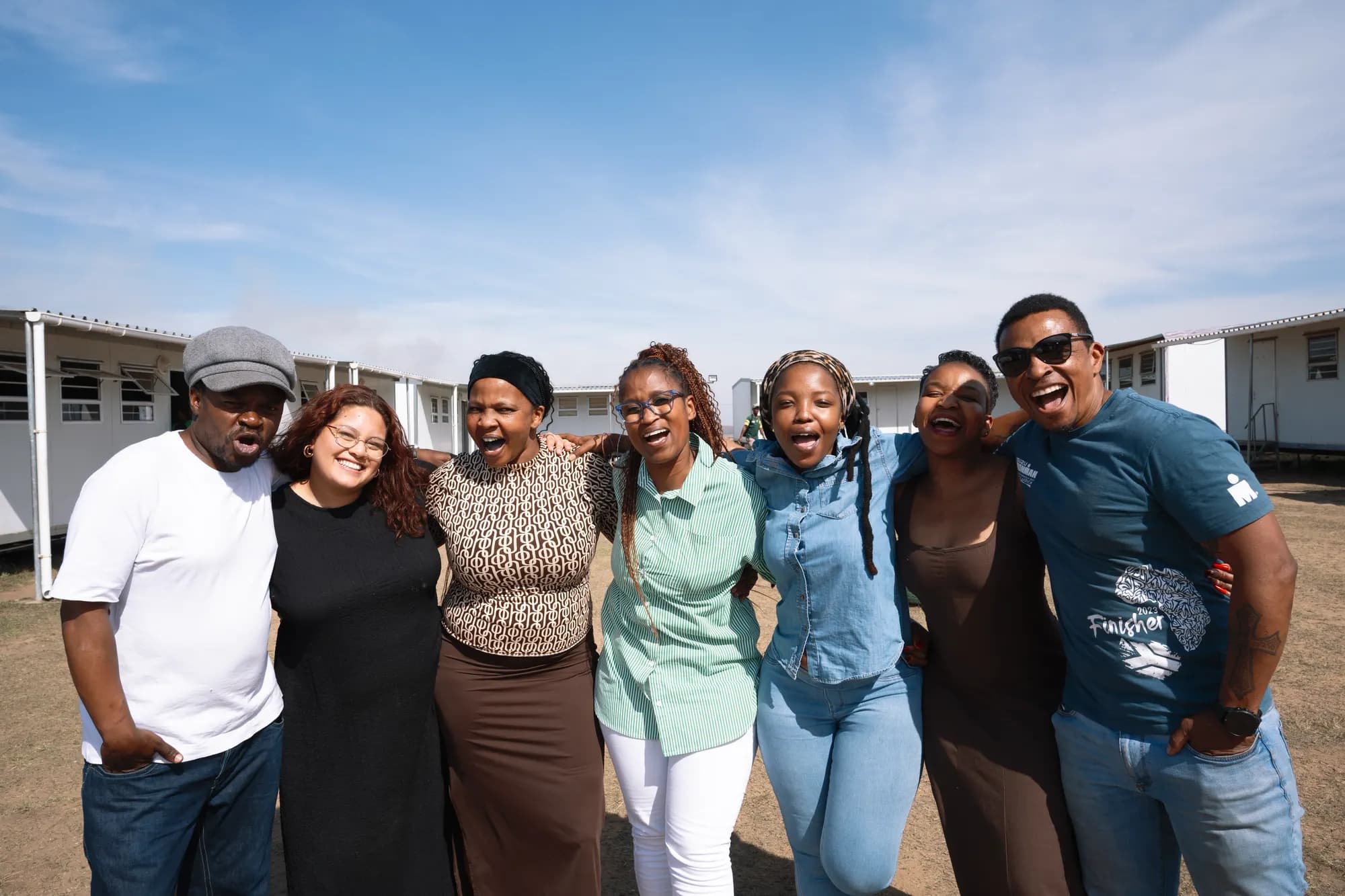 The Phakamani team together outside a school, arms around each other and laughing